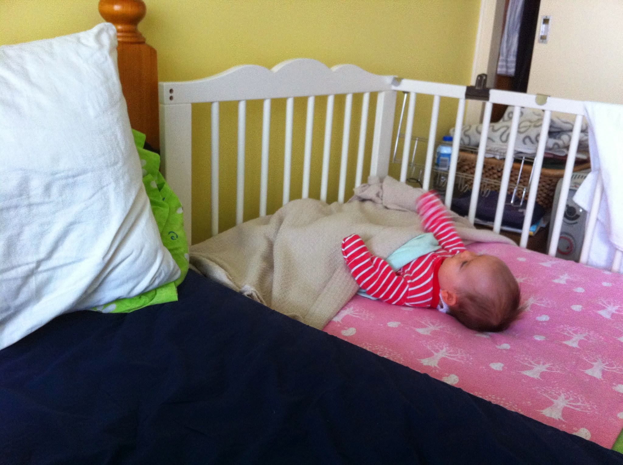 Baby girl sleeping in a DIY sidecar crib attached to a double bed, safe co-sleeping setup